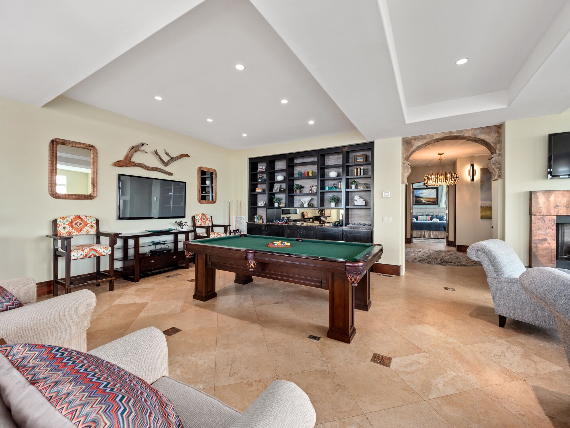 A spacious living room with a pool table, comfortable seating, a television, and a fireplace.