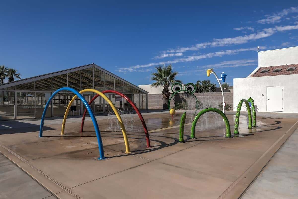 A water feature with colorful arches and a glass building in the background.