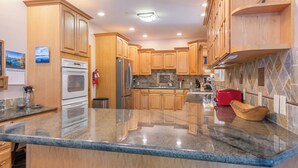 A modern kitchen with wooden cabinets, granite countertops, stainless steel appliances, and a tiled backsplash. - Luxury Family Home, Hot Tub, Garage, Family Room, Near Tahoe City in Carnelian Bay (Carnelian Bay)