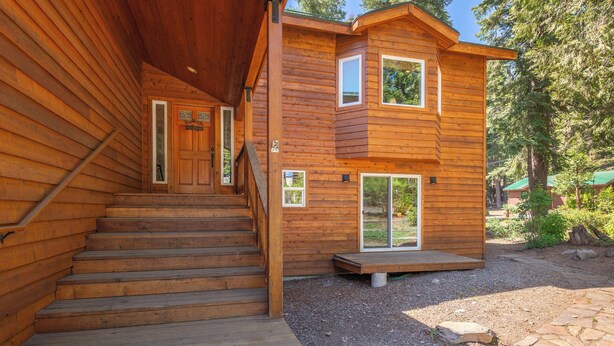 A wooden cabin with a staircase leading to a front door, a deck, and a stone pathway. - Luxury Family Home, Hot Tub, Garage, Family Room, Near Tahoe City in Carnelian Bay (Carnelian Bay)