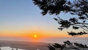 A sunset over a calm body of water with trees framing the view. - Garden Pond Retreat~Hot tub & Fire Pit! (Mckinleyville)