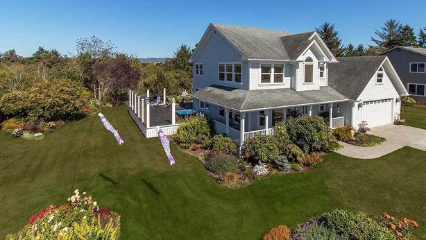 A large, two-story house with a covered porch and a well-maintained lawn. - Garden Pond Retreat~Hot tub & Fire Pit! (Mckinleyville)