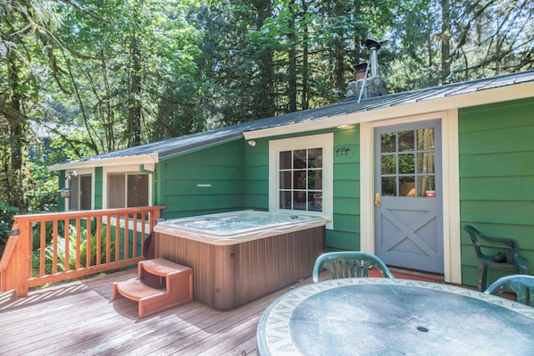 A hot tub on a wooden deck with a view of a forest.