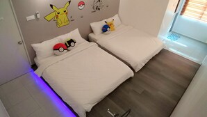 Une chambre avec deux lits, du linge de lit blanc et des autocollants muraux sur le thème de Pokémon.