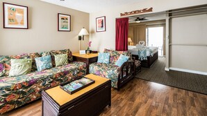 Una habitación de hotel con sofá, cama, una mesita de madera y ventilador de techo.