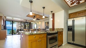 Una cocina moderna con una isla grande, electrodomésticos de acero inoxidable y vistas al exterior.