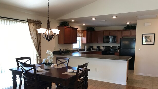 A spacious kitchen with wooden cabinets, a central island, and a dining area with a dark wooden table and chairs.