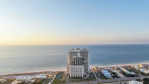 Un hôtel de grande hauteur, avec de nombreux étages, une vue sur la plage et un espace de stationnement.