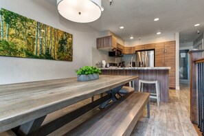 A modern kitchen with wooden cabinets, a stainless steel refrigerator, and a large island with bar stools.