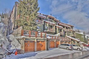 A multi-story building with balconies, wooden garage doors, and a parked car.