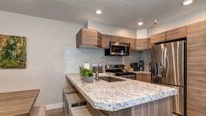 A modern kitchen with a granite countertop, stainless steel appliances, and wooden cabinetry. - Central Location, Perfect for Large Groups & Recreation! Park City Woodside Ski Estate (Ski-in/out) (Park City)