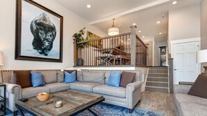 A living room with a sectional sofa, a coffee table, and a large painting of a bison. - Central Location, Perfect for Large Groups & Recreation! Park City Woodside Ski Estate (Ski-in/out) (Park City)