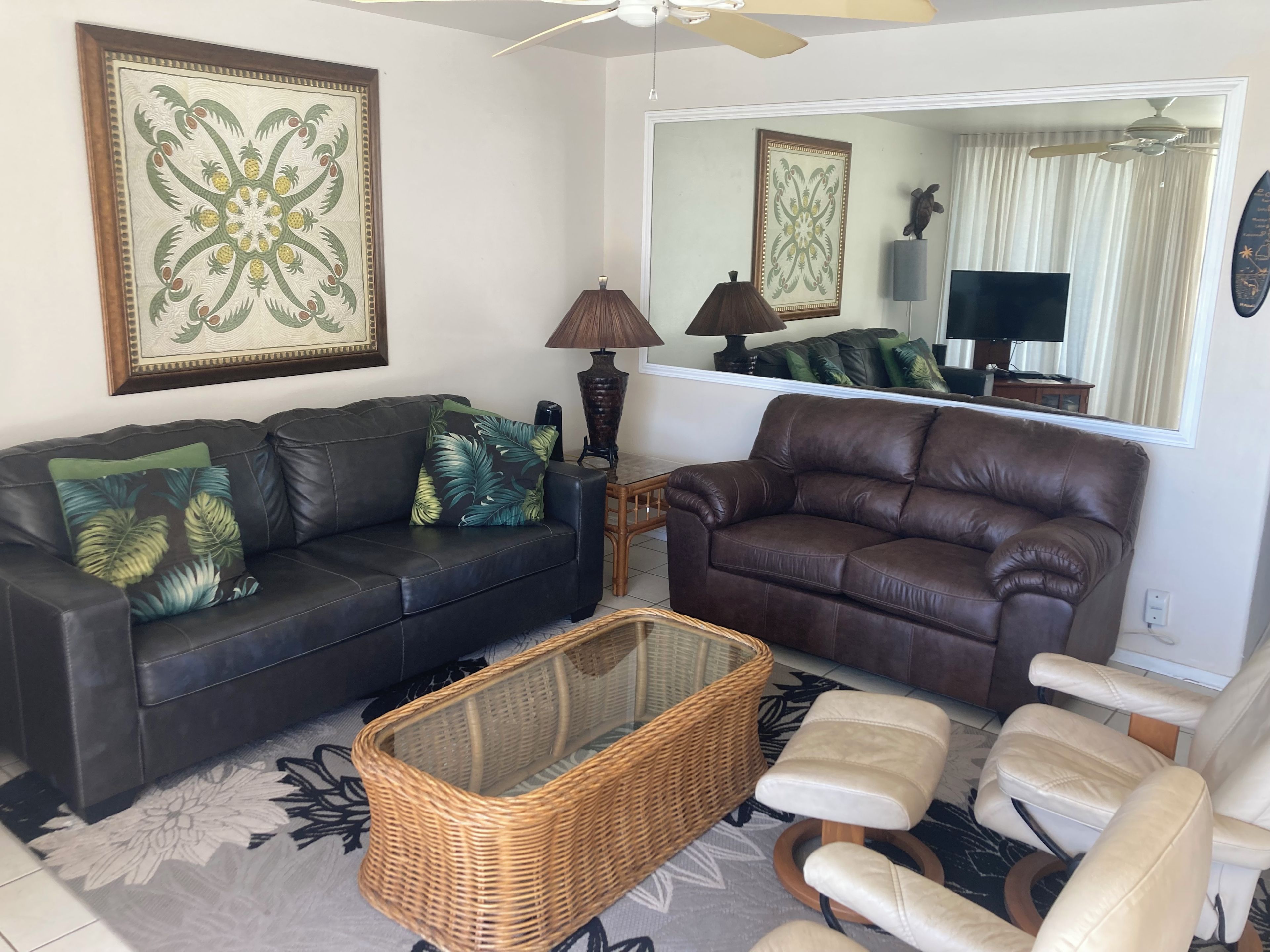 A living room with a brown leather sofa, a wicker coffee table, and a white armchair.