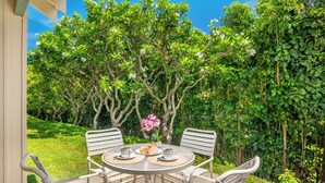 A round table with four chairs, a vase with pink flowers, and a plate with pastries. - Manualoha 606 AC Throughout By Suite Paradise (Koloa)