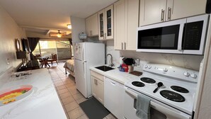 A compact kitchen with a refrigerator, microwave, stove, and sink.