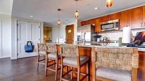 A modern kitchen with wooden cabinets, stainless steel appliances, and a central island with bar stools.