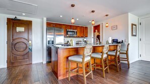 Une cuisine moderne avec des meubles en bois, des appareils en acier inoxydable et un coin bar agrémenté de chaises en osier.