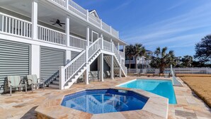 Una casa de dos pisos con un patio cubierto, una piscina y un jacuzzi.