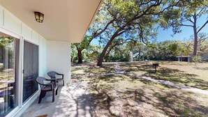 A covered patio with a table and chairs, a mailbox, and a large tree in the background.