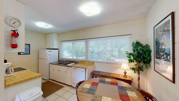 A compact kitchen with a refrigerator, sink, and a small dining table.