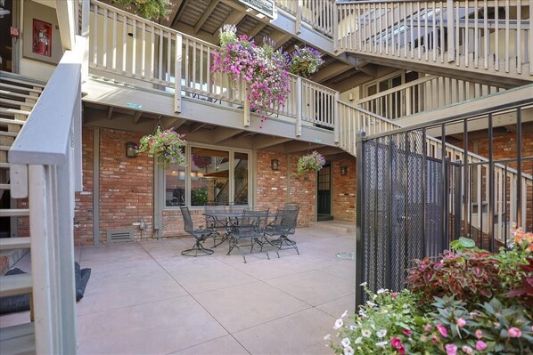 A multi-level outdoor patio with a brick wall, a table with chairs, and hanging flower baskets. - Chateau Chaumont 14 | 3BR/2BA Aspen | Hot Tub (Aspen)