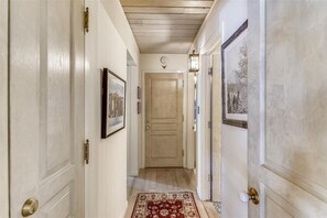 A hallway with wooden doors, a patterned rug, and a framed picture on the wall. - Chateau Chaumont 14 | 3BR/2BA Aspen | Hot Tub (Aspen)