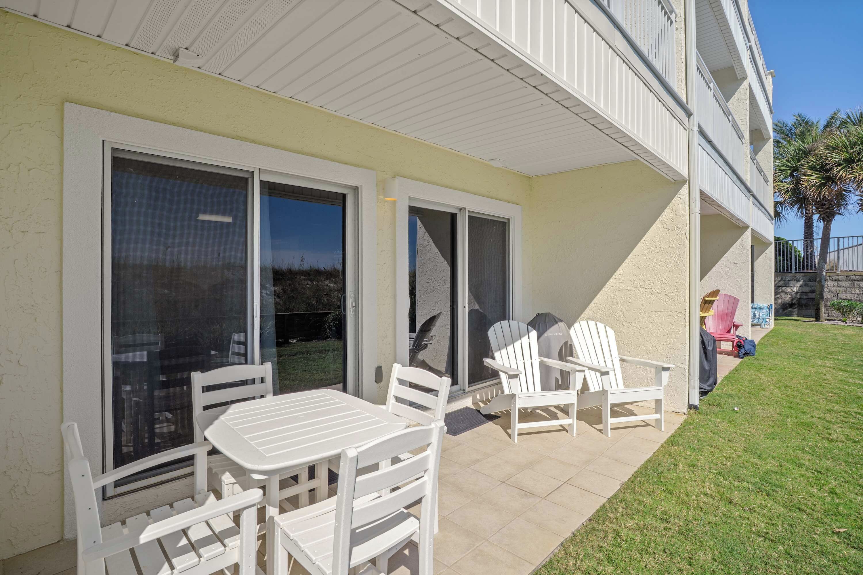 Un patio couvert avec une table et des chaises, une porte-fenêtre coulissante et une vue sur les environs.