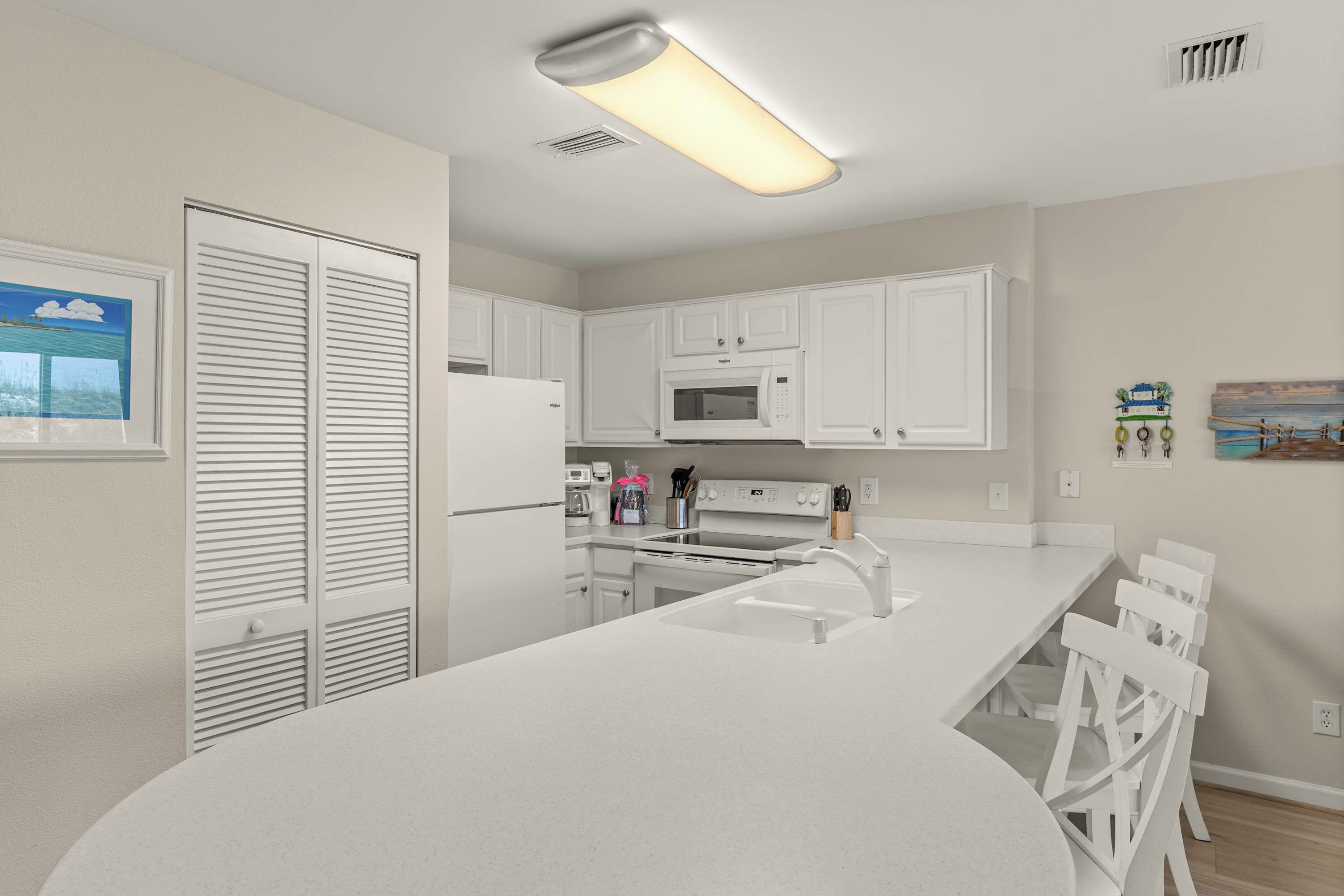 A modern kitchen with white cabinetry, a built-in microwave, and a stainless steel range hood.