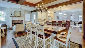 Un comedor amplio con una gran mesa de madera, sillas blancas y una araña.