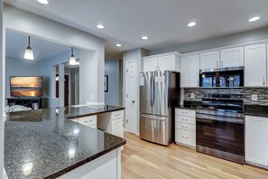 A modern kitchen with stainless steel appliances, white cabinetry, and a granite countertop.