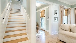 A staircase with white railings leading to a room with a beige sofa and a wooden floor. - The WaterColor Escape You've Been Dreaming Of – Remodeled Kitchen/Golf Cart (Santa Rosa Beach)