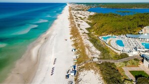 An aerial view of a beach resort with a long sandy beach, a pool area, and a clear blue sky. - The WaterColor Escape You've Been Dreaming Of – Remodeled Kitchen/Golf Cart (Santa Rosa Beach)