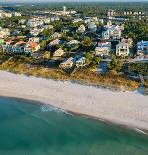 An aerial view of a coastal residential area with houses, a beach, and a water tower.