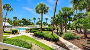 A pool area with palm trees, a bridge, and a well-maintained lawn. - 433 Captains Walk- Completely Renovated - Oceanfront Villa in Palmetto Dunes! (Hilton Head Island)