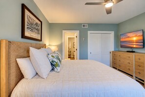 A bedroom with a bed, a ceiling fan, a TV, and a dresser. - 433 Captains Walk- Completely Renovated - Oceanfront Villa in Palmetto Dunes! (Hilton Head Island)