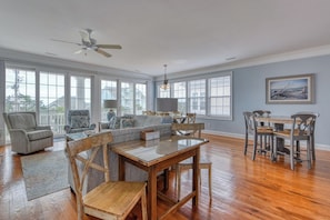 A spacious living room with a wooden dining table, a sofa, and a ceiling fan. - Starboard - Six Bedroom, Five-and-a-Half-Bath Beach House with Community Pool (Garden City Beach)