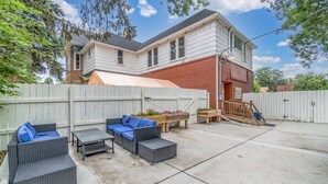 A backyard with a white fence, outdoor furniture, and a wooden deck.