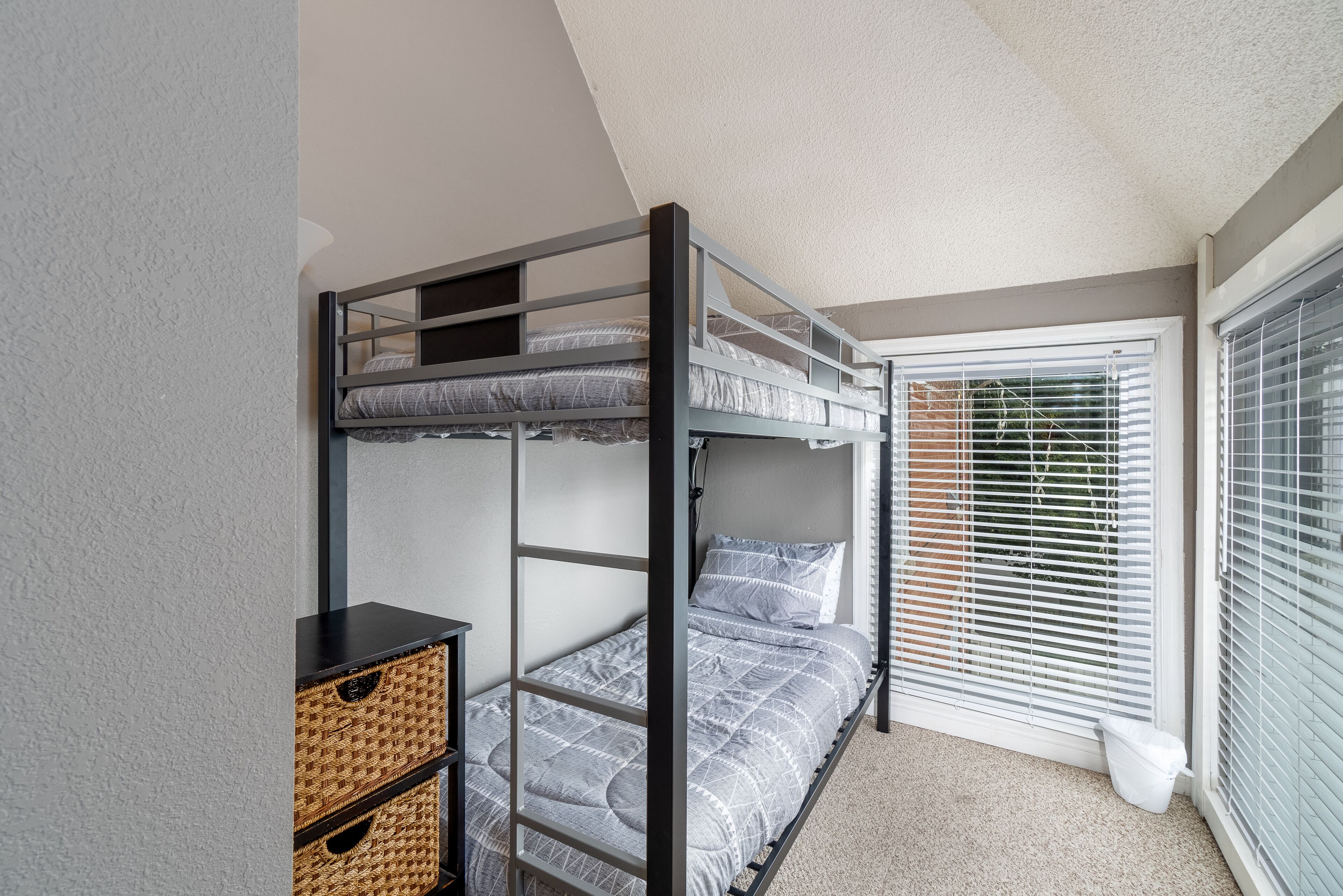 A bunk bed room with a window and a small table with baskets.