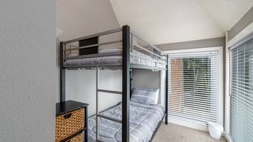 A bunk bed room with a window and a small table with baskets.