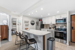 A modern kitchen with a central island, stainless steel appliances, and a white backsplash.
