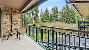 A balcony with stone walls, a table with chairs, and a view of trees. - Newly Renovated with Immaculate Updates. Winter Ski In/Out. TE102 (Breckenridge)