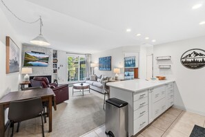 A modern kitchen with white cabinets, a built-in island, and a dining area with a table and chairs.