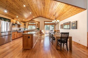 A spacious kitchen with wooden cabinets, a large island, and a dining area with chairs and a table.