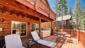 A wooden deck with lounge chairs and a hot tub.