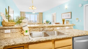 A kitchen with granite countertops, stainless steel sink, and wooden cabinets. - 🏖️Ariel Dunes I 1502 | 3BR • Pools • Gulf View • Seascape Beach🏖️ (Miramar Beach)