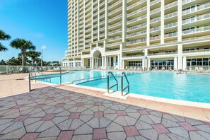 A large hotel with multiple balconies and a swimming pool area.