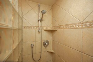 A shower with a handheld showerhead and a wall-mounted control.