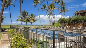 A pool area with lounge chairs, a fenced pool, and palm trees. - Waiohuli Beach Hale #D-120 Steps to Beach Oceanfront Complex with Great Rates (Kihei)