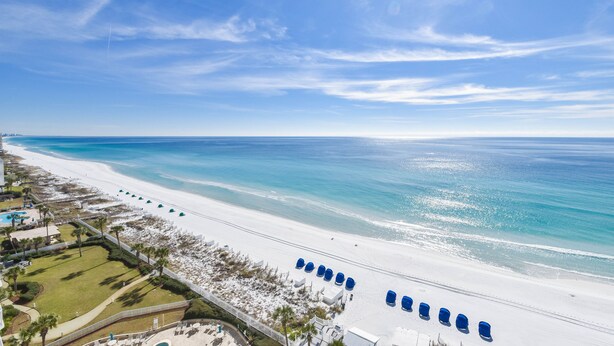 A beach resort with a long stretch of white sand, clear blue water, and a row of blue beach chairs. - Updated Modern Beachfront Condo w/ Stunning Gulf Views in Destin! 🌴☀🌊 (Destin)