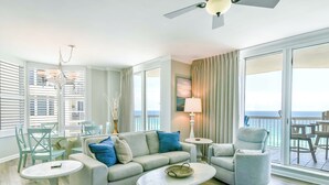 A spacious living room with a sofa, armchairs, and a coffee table. There is a balcony with a view of the ocean. - Updated Modern Beachfront Condo w/ Stunning Gulf Views in Destin! 🌴☀🌊 (Destin)